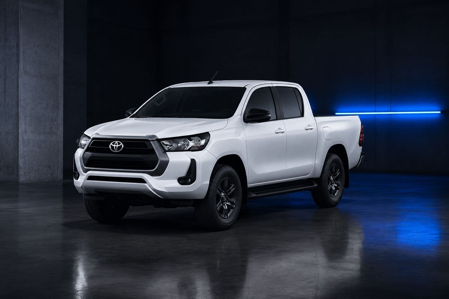 Toyota Hilux cabine dupla branca em galpão de concreto com faixa de luz azul ao fundo